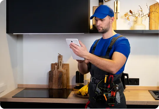 repairman diagnosing an electric induction hob while using a tablet